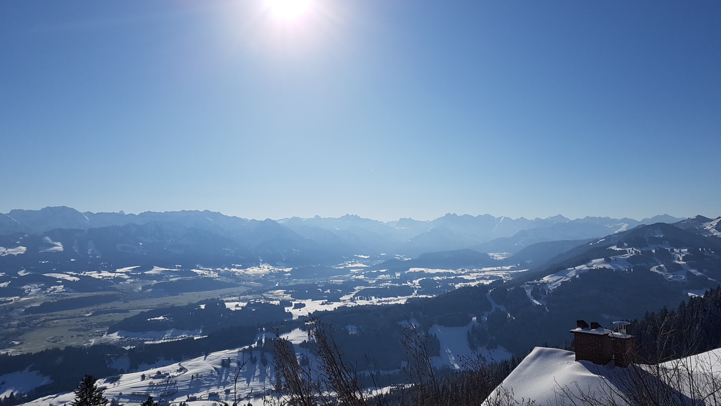 winterlicher Panorama-Blick über sonnige verschneite Bergwelt 